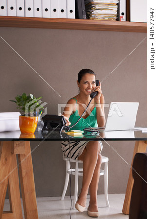 Phone call, smile and landline with woman employee in office for communication or reception. Laptop, remote work and happy young secretary answering telephone in small business or startup workplace Phone call, smile and landline with woman employee in office for communication or reception. Laptop, remote work and happy young secretary answering telephone in small business or startup workplace 140577947