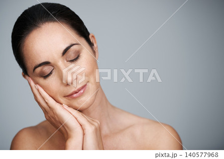 Beauty, mature and skincare of woman touching face in makeup at studio isolated on gray background. Eyes closed, cosmetics or glow of model in facial treatment for dermatology, anti aging or mockup Beauty, mature and skincare of woman touching face in makeup at studio isolated on gray background. Eyes closed, cosmetics or glow of model in facial treatment for dermatology, anti aging or mockup 140577968