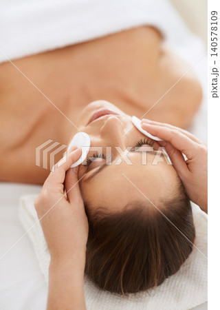 Woman, pad and facial massage for cosmetics treatment to relax, cleaning and beauty therapy for skin care. Female person, calm and serene or dermatology, closeup and rest at hotel and peace or zen 140578109