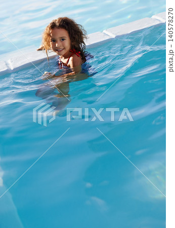Child, girl and water with face, swimwear and blue summer sky for relax and smile. Kid, pool and sunshine with happiness, outdoor and play with curly hair and fun for sunny positivity and childhood Child, girl and water with face, swimwear and blue summer sky for relax and smile. Kid, pool and sunshine with happiness, outdoor and play with curly hair and fun for sunny positivity and childhood 140578270