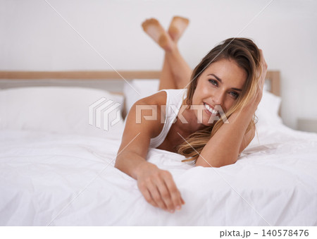 Portrait, smile and woman in bed in home to relax or wake up in the morning in apartment in Spain. Face, happy and young person in bedroom for resting or lying on comfortable sheets in house alone 140578476