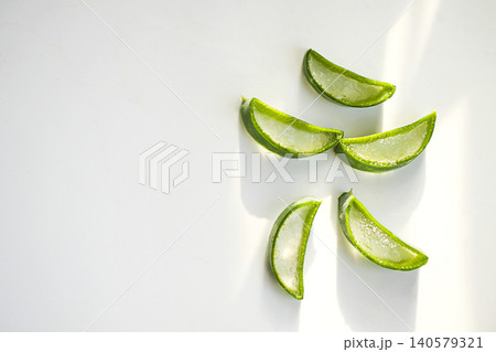 Fresh green aloe vera slices arranged on a clean white surface with soft natural light highlighting their texture and color 140579321
