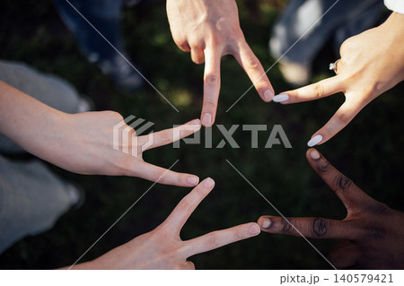 Diverse group of hands forming a star shape with fingers, showcasing unity and collaboration on a grassy outdoor surface in a natural setting Diverse group of hands forming a star shape with fingers, showcasing unity and collaboration on a grassy outdoor surface in a natural setting 140579421
