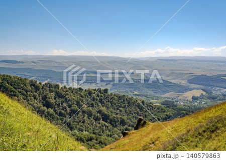 Panoramic view of the green valley and the snowy peak of Mount Elbrus on the horizon against the blue sky on a sunny clear morning in Kislovodsk Stavropol territory, Russia Panoramic view of the green valley and the snowy peak of Mount Elbrus on the horizon against the blue sky on a sunny clear morning in Kislovodsk Stavropol territory, Russia 140579863