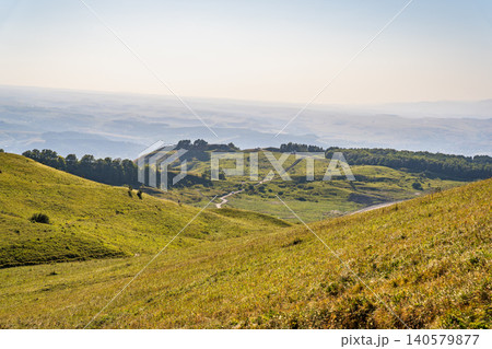 Layers of green mountains and hills in the haze during sunset. Panoramic View of Green hills and Meadow. 140579877