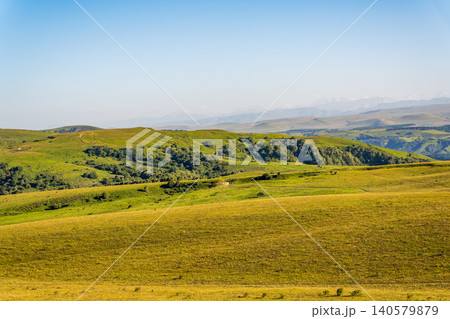 Layers of green mountains and hills in the haze during sunset. Panoramic View of Green hills and Meadow. 140579879