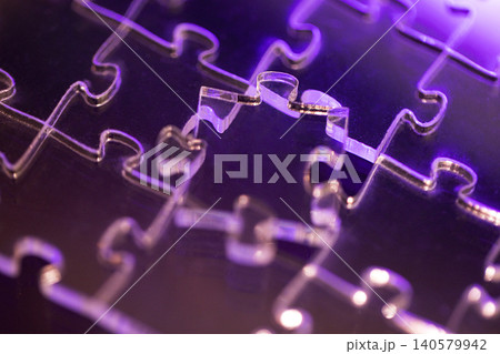 Close-up view of transparent jigsaw puzzle pieces with a purple light background highlighting the intricate shapes and connections between the pieces Close-up view of transparent jigsaw puzzle pieces with a purple light background highlighting the intricate shapes and connections between the pieces 140579942