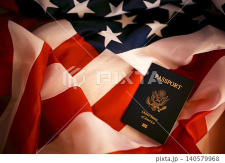 United States passport resting on folded American flag with red and white stripes and blue field featuring white stars, symbolizing national identity and travel United States passport resting on folded American flag with red and white stripes and blue field featuring white stars, symbolizing national identity and travel 140579968