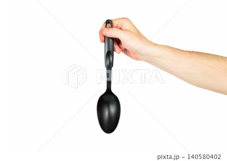 black plastic kitchen spoon vertically in a hand on a white background 140580402