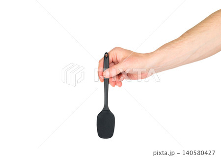 male hand holds a black kitchen silicone spatula vertically down on a white background male hand holds a black kitchen silicone spatula vertically down on a white background 140580427