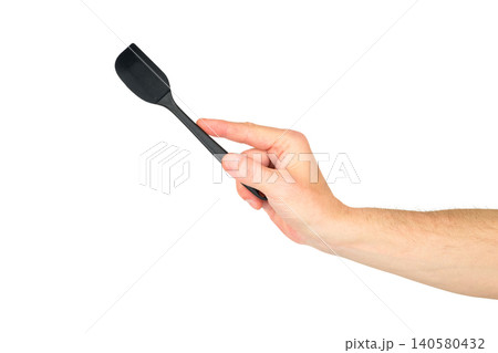 a male hand pointing a black kitchen spatula upward at an angle on a white background a male hand pointing a black kitchen spatula upward at an angle on a white background 140580432