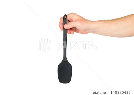 a male hand holding a wide black cooking spatula against a plain white background a male hand holding a wide black cooking spatula against a plain white background 140580435
