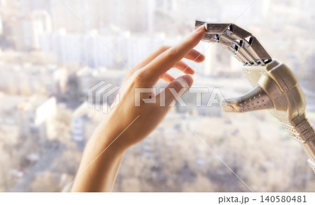 Human hand reaching towards a robotic prosthetic hand in a bright urban setting, showcasing advanced technology and innovation in assistive devices Human hand reaching towards a robotic prosthetic hand in a bright urban setting, showcasing advanced technology and innovation in assistive devices 140580481