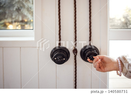 Hand of a person reaching for a vintage door handle with a rustic design, showcasing the charm of traditional architecture and inviting warmth into the space 140580731