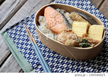 曲げわっぱに入れた焼き鮭の和食弁当と矢絣柄の包み布 曲げわっぱに入れた焼き鮭の和食弁当と矢絣柄の包み布 140580825