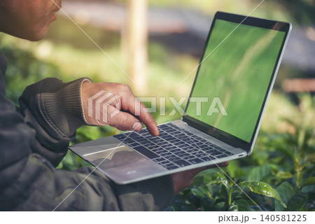 Smart farmer using laptop in eco green farm sustainable quality control. Close up Hand typing laptop computer quality control plant tree. Farmer hands using technology in eco Farmland biotechnology 140581225