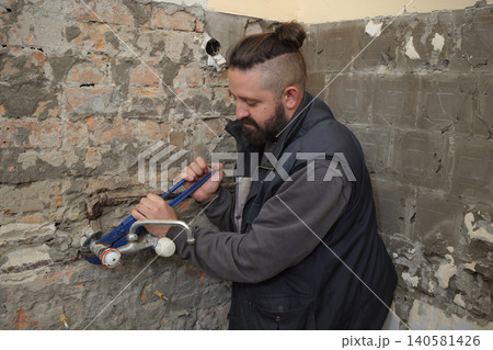 Plumber fixing old tap in a bathroom using adjustable wrench Plumber fixing old tap in a bathroom using adjustable wrench 140581426