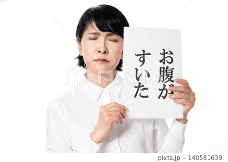お腹がすいたと書かれた紙を持ち元気のない様子の中年女性 お腹がすいたと書かれた紙を持ち元気のない様子の中年女性 140581639