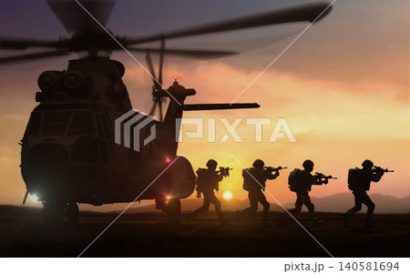 silhouette of military special force unit on a mission with helicopter in background under sunset sky 140581694