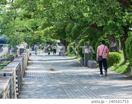 初夏の朝の犬山市の木曽川遊歩道で歩くシニア男性と散歩客の姿 140581753
