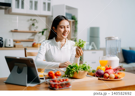 Asian woman preparing fresh salad, reflecting healthy lifestyle, clean eating, nutrition, organic vegetables, and modern home kitchen environment. Asian woman preparing fresh salad, reflecting healthy lifestyle, clean eating, nutrition, organic vegetables, and modern home kitchen environment. 140582692