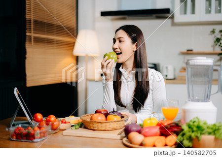 Smiling young woman preparing fresh strawberries, fruit and vegetables in a modern kitchen. Healthy lifestyle, clean eating, vegan nutrition and home cooking concept. Smiling young woman preparing fresh strawberries, fruit and vegetables in a modern kitchen. Healthy lifestyle, clean eating, vegan nutrition and home cooking concept. 140582705