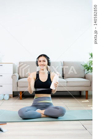 Smiling woman doing home fitness workout with tablet and headphones, showing thumbs up. Online training, healthy lifestyle, wellness and digital exercise concept. Smiling woman doing home fitness workout with tablet and headphones, showing thumbs up. Online training, healthy lifestyle, wellness and digital exercise concept. 140582850