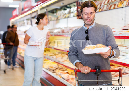 Man choosing packaged chicken in supermarket Man choosing packaged chicken in supermarket 140583062