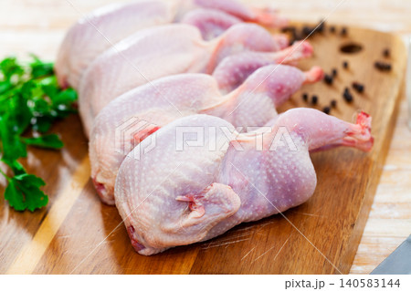 Raw gutted partridges on wooden table with seasonings and greens Raw gutted partridges on wooden table with seasonings and greens 140583144
