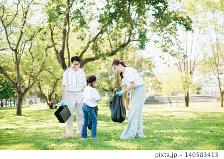 Joyful family volunteering to clean up a green park together. A positive lifestyle scene promoting eco-awareness, teamwork, and love for nature. Joyful family volunteering to clean up a green park together. A positive lifestyle scene promoting eco-awareness, teamwork, and love for nature. 140583413