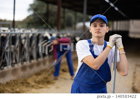 Portrait of positive male farm worker in cowshed 140583422
