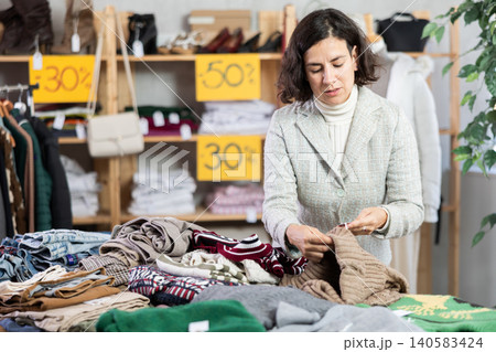 Latin American woman search and choose knitted jumper in shop Latin American woman search and choose knitted jumper in shop 140583424