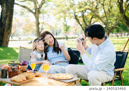 Joyful family picnic moment as daughter takes photo of smiling parents raising orange juice in a sunny park. A warm, happy lifestyle full Joyful family picnic moment as daughter takes photo of smiling parents raising orange juice in a sunny park. A warm, happy lifestyle full 140583468