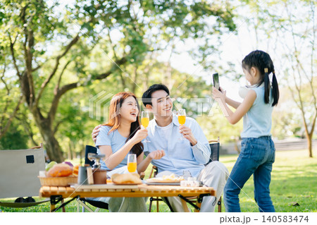 Joyful family enjoying coffee and snacks during a picnic in a sunny green park. A warm, happy lifestyle moment full of love, laughter Joyful family enjoying coffee and snacks during a picnic in a sunny green park. A warm, happy lifestyle moment full of love, laughter 140583474