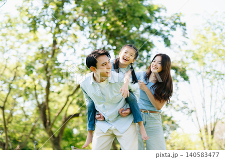 Joyful family playing together in a sunny green park. A candid outdoor moment full of love, laughter, and connection 140583477