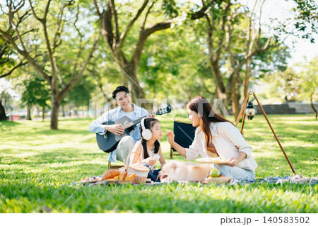 Cheerful family picnic with guitar, food, and fluffy dog in a sunny green park. A joyful outdoor lifestyle moment filled with music, warmth, and love. Cheerful family picnic with guitar, food, and fluffy dog in a sunny green park. A joyful outdoor lifestyle moment filled with music, warmth, and love. 140583502