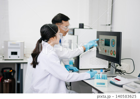 Two Asian Scientists Analyzing Data on Computer Monitor in Modern Laboratory Two Asian Scientists Analyzing Data on Computer Monitor in Modern Laboratory 140583625