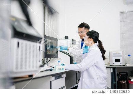 Two Asian Scientists Analyzing Data on Computer Monitor in Modern Laboratory Two Asian Scientists Analyzing Data on Computer Monitor in Modern Laboratory 140583626