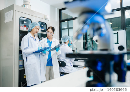 Team scientist or medical technician working, having a medical discuss meeting with an Asian senior female scientist supervisor Team scientist or medical technician working, having a medical discuss meeting with an Asian senior female scientist supervisor 140583666