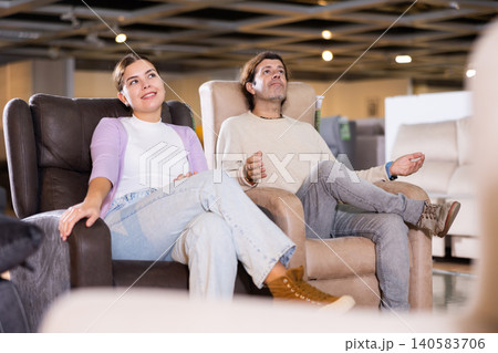 Man and woman sitting around in armchairs in furniture store Man and woman sitting around in armchairs in furniture store 140583706