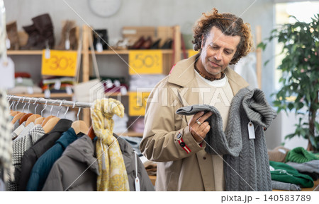 Man search and choose knitted sweater in store Man search and choose knitted sweater in store 140583789