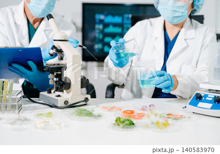 Dynamic scene of food scientists using microscopes and pipettes in a lab Dynamic scene of food scientists using microscopes and pipettes in a lab 140583970