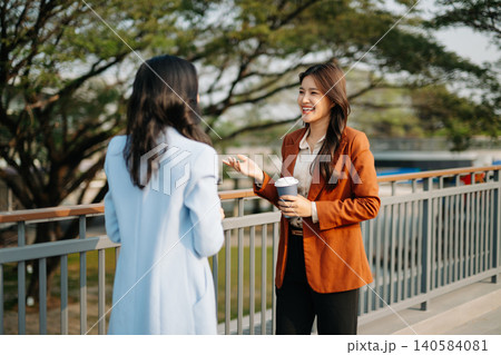 Two Asian businesswomen collaborating with digital tablet outdoors in modern corporate setting. Teamwork, technology, leadership Two Asian businesswomen collaborating with digital tablet outdoors in modern corporate setting. Teamwork, technology, leadership 140584081