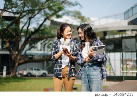Asian students using smartphone and tablet at modern campus. Social media, digital communication, online networking and Gen Z lifestyle in university setting. Asian students using smartphone and tablet at modern campus. Social media, digital communication, online networking and Gen Z lifestyle in university setting. 140584215