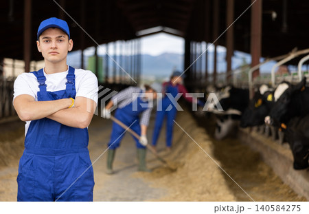 Portrait of positive male farm worker in cowshed 140584275