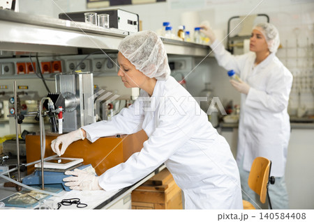 Focused female lab technician working with scales Focused female lab technician working with scales 140584408