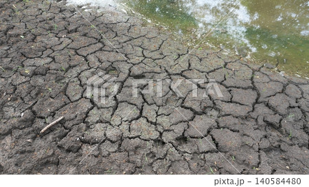 Cracked Dry Soil Beside Water During Drought Cracked Dry Soil Beside Water During Drought 140584480