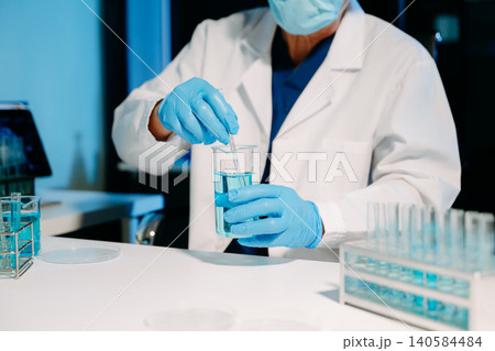 scientists in lab coats conducting research, handling glassware, and working with chemicals in a modern, high tech laboratory. scientists in lab coats conducting research, handling glassware, and working with chemicals in a modern, high tech laboratory. 140584484