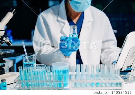 scientists in lab coats conducting research, handling glassware, and working with chemicals in a modern, high tech laboratory. scientists in lab coats conducting research, handling glassware, and working with chemicals in a modern, high tech laboratory. 140584515