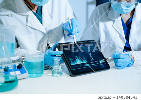 Scientists analyzing DNA genetics data on tablet in biotechnology laboratory with microscope and test tubes. Medical research, healthcare technology Scientists analyzing DNA genetics data on tablet in biotechnology laboratory with microscope and test tubes. Medical research, healthcare technology 140584543